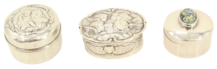 (3) Silver Pill Boxes - 2.855 ozt.: Lot comprised of three silver circular pill boxes. One box with mother and child on lid; one box with group of cherubs; one decorated with crushed stone and enamel.Size: 2 1/8 x 1 5/8 x 1 in. Largest.