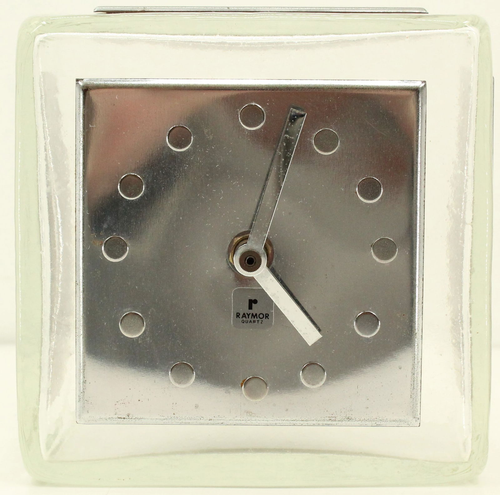 Square Raymor Quartz Clock: Square Raymor Quartz Clock. Silver face plate with dots as the numbers. Battery operated. As Is: Chip on top. Size: 6 x 4 3/8 x 6 1/8 in. #5799 #26 Location C2