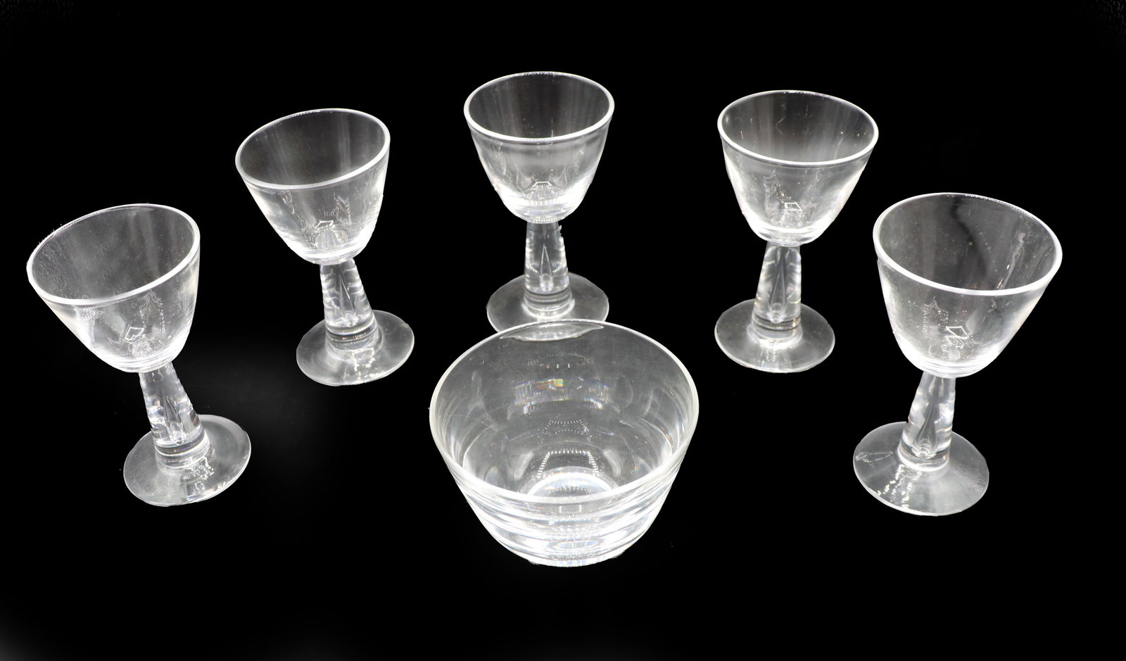 (5) Steuben Glass Wine Glasses & 1 Bowl: (5) Steuben Glass Wine Glasses & 1 Bowl. Marked on underside. Teardrop air bubble in stem of glasses. Simple design. Size (Bowl): 4 1/2 x 4 1/2 x 3 inSize (Cup): 3 x 3 x 5 in. Steuben Glass is an Amer