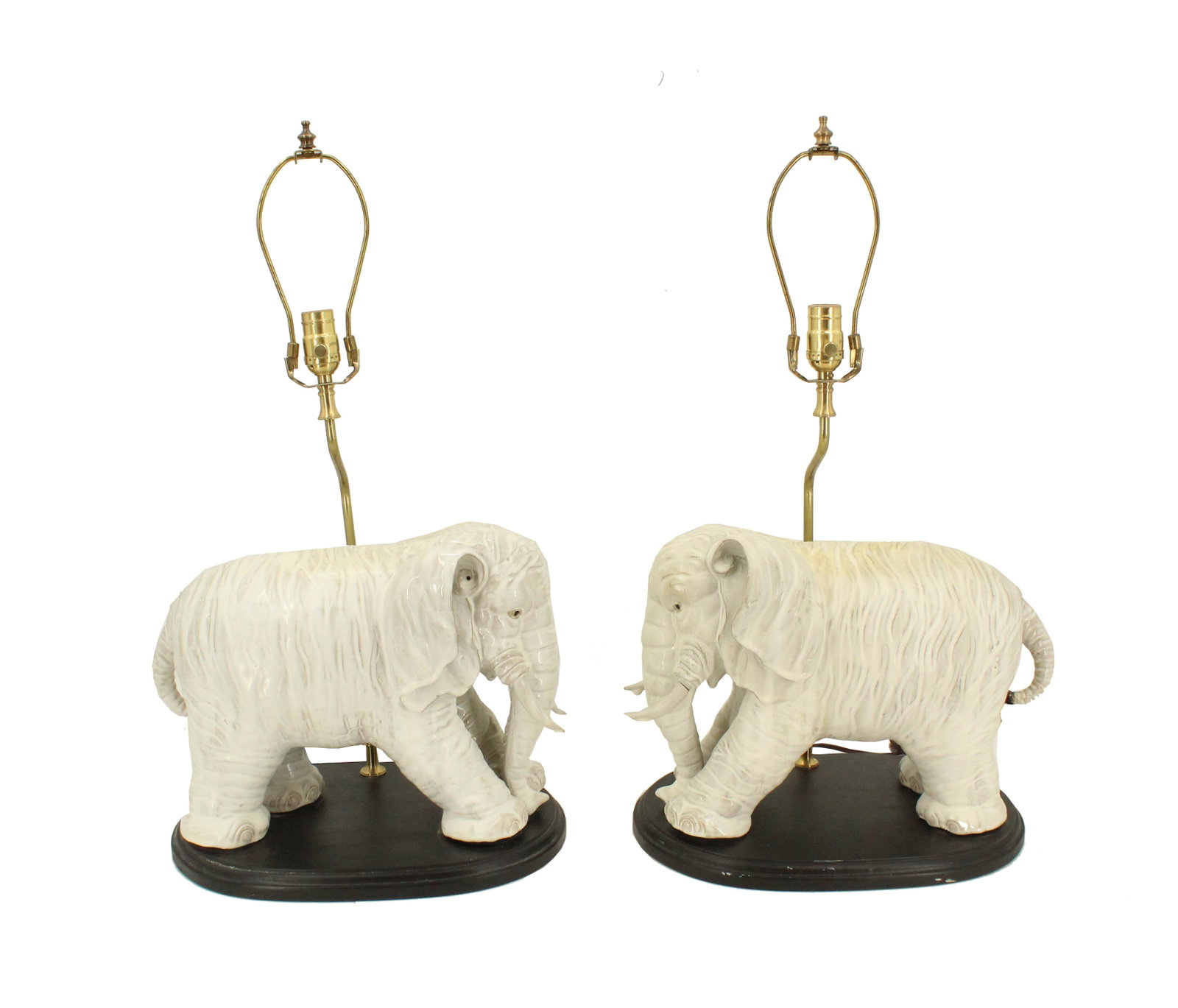 Pair of Elephant Ceramic Table Lamps: Pair of Elephant Ceramic Table Lamps. Hollywood Regency Style. Brass light fixtures raise up behind the elephants creating a glowing surface looking down at the elephants. They sit on a brown woo
