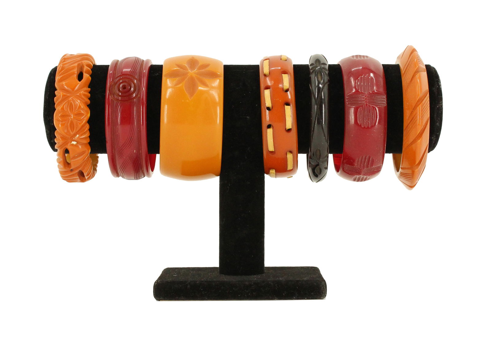 (7) Multicolored Bakelite Bangles: (7) Multicolored Bakelite Bangles. From left to right: Solid orange with carved floral pattern. Deep translucent red with a grooved texture running horizontally around the bangle.&nb