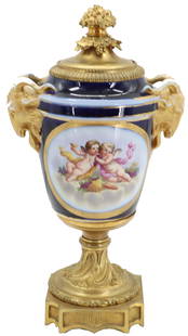 Late 19th Early 20th Century French Sevres Style Porcelain and Gilt Bronze Covered Urn: Late 19th Early 20th Century French Sevres Style Porcelain and Gilt Bronze Covered Urn / Vase. Ram head masks on either side terminating in an exuberant gilt bronze floral finial. Well painted playful