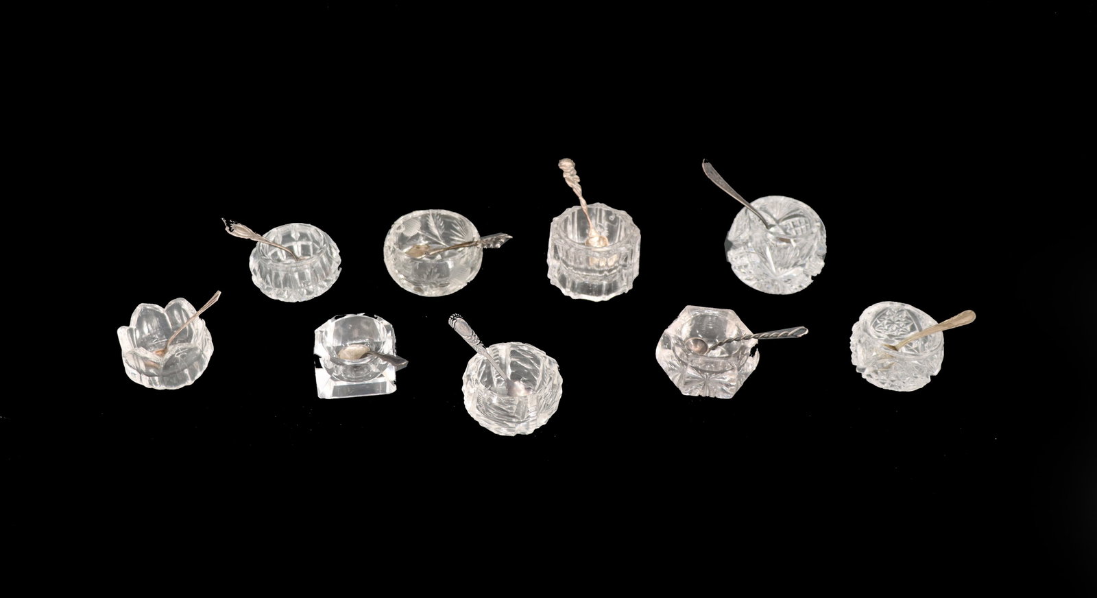 (9) Cut Glass Salt Cellars and Sterling Silver Spoons - 0.855 ozt: (9) Cut Glass Salt Cellars and Sterling Silver Spoons - 0.855 ozt. The glass pieces are all different shapes and sizes and unmarked. The spoons are also all different shapes and sizes. Condition: Over