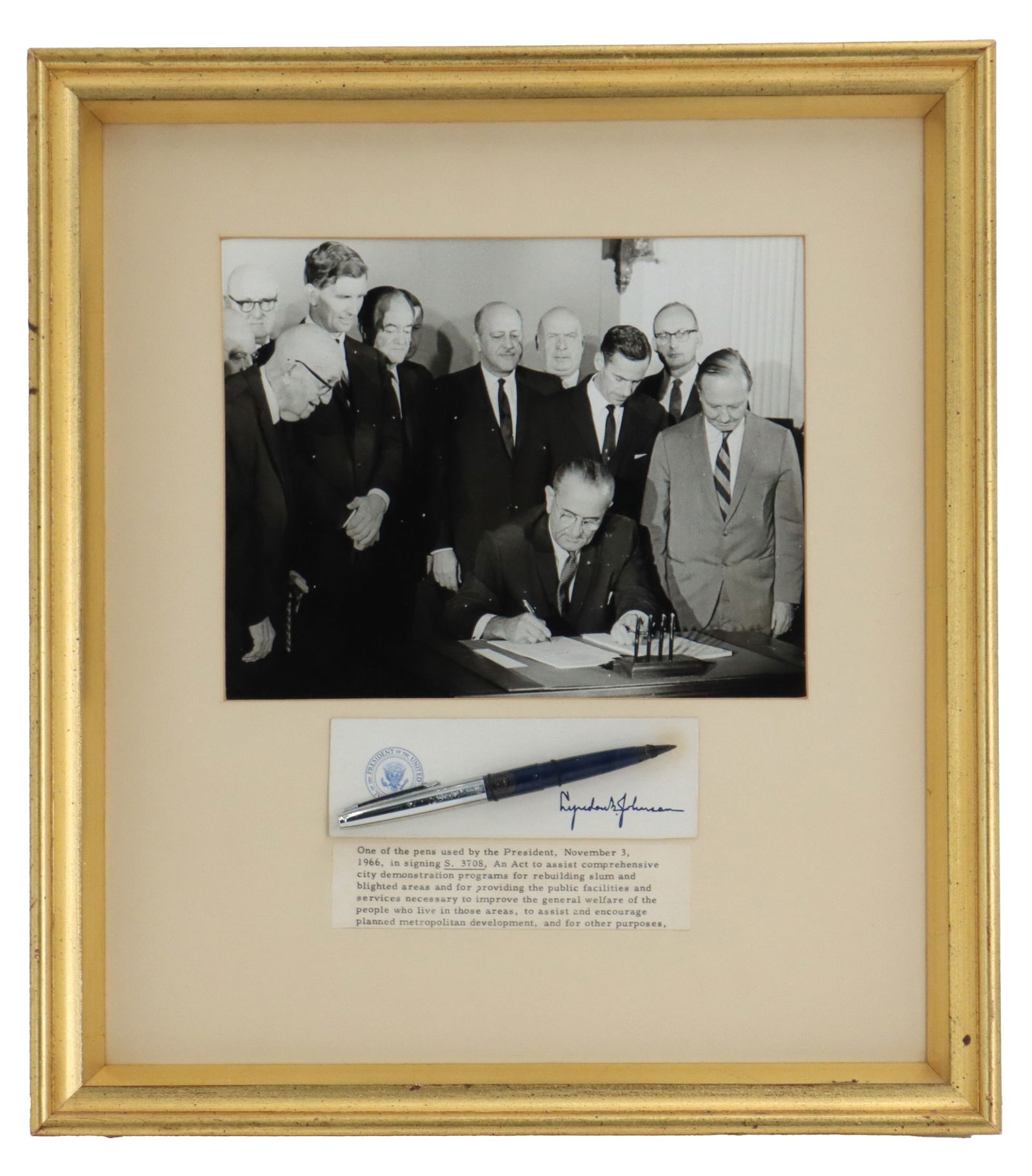 Framed Lyndon B. Johnson Commemorative Photograph and Pen Used in Signing: Framed Lyndon B. Johnson Commemorative Photograph and Pen Used in Signing. Includes the black-and-white photo of the president surrounded by others as he signs, and the pen itself against official Whi