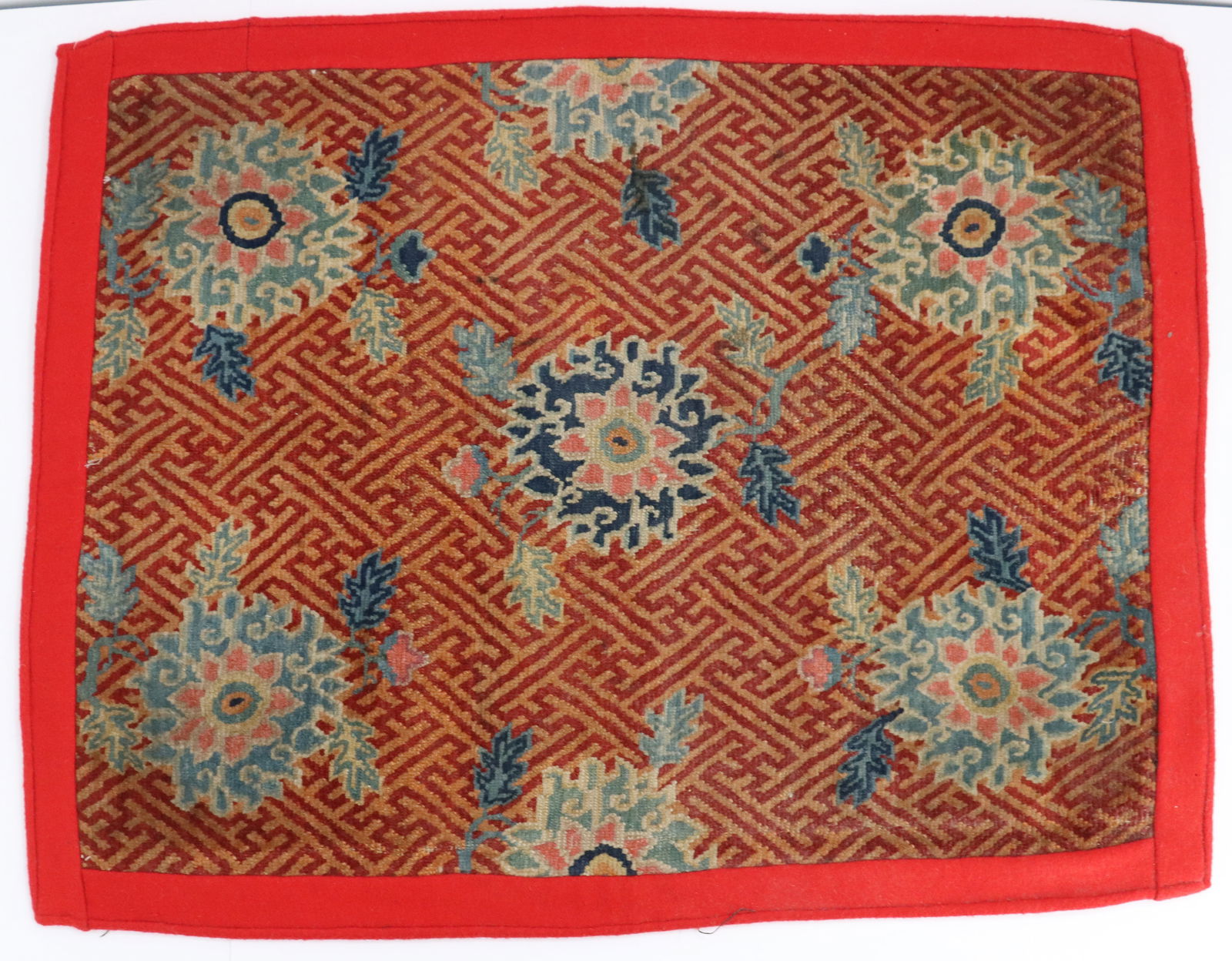 Tibetan Wool Floor Mat: Tibetan Wool Floor Mat. Bright red border around traditional design combining geometrically linked patterns and floral shapes, possibly cut from a larger piece of fabric at some point. Size:&nbs