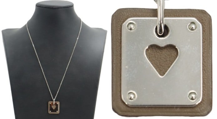 One Hermes As de Coeur Necklace: One Hermes As de Coeur Necklace. Palladium-plated hardware and calfskin leather in brown. Front of the pendant is detailed with four polished studs and a central heart shaped cutout. Comes with origin