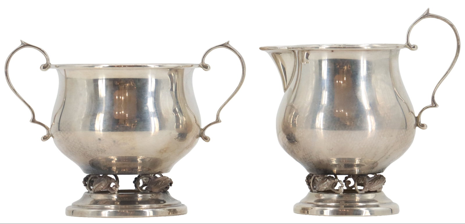 Revere Silversmiths Sterling Silver Creamer and Sugar Bowl - 6.940 ozt.: Revere Silversmiths Sterling Silver Creamer and Sugar Bowl - 6.940 ozt. Identical design, with a hollow vine and bud design between the foot and body of each and a stylized curve in the handles.