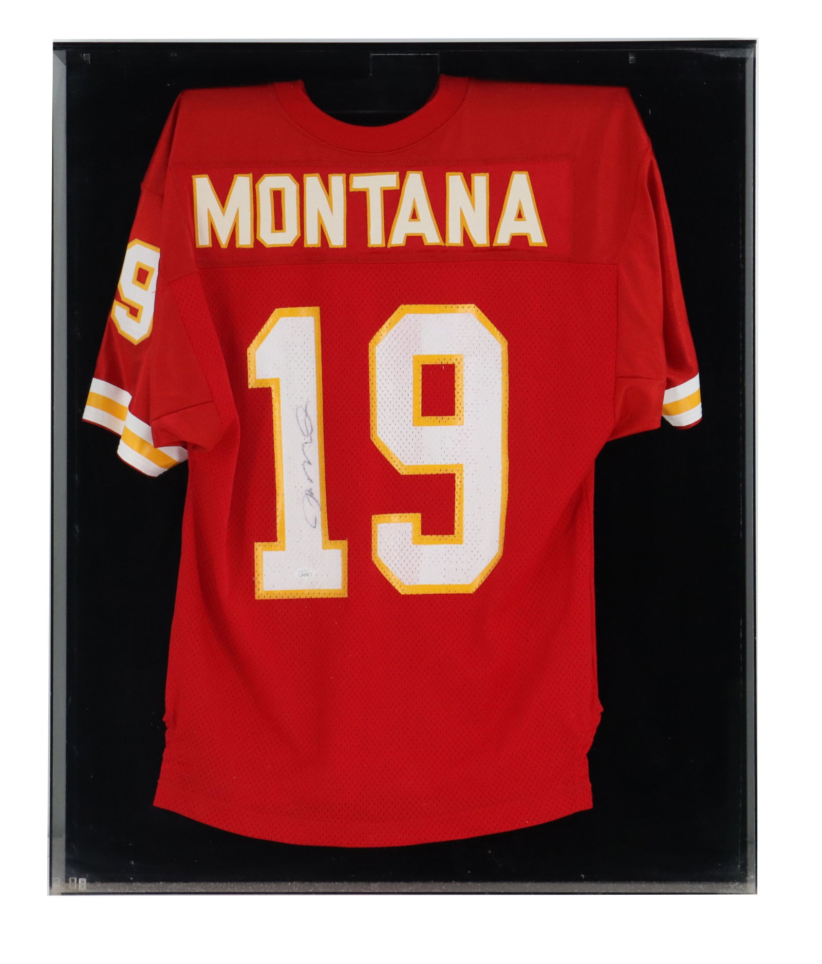 Signed Joe Montana Kansas City Chiefs Replica Jersey: Signed Joe Montana Kansas City Chiefs Replica Jersey. Signed, red Kansas City Chiefs jersey belonging to Joe Montana, featuring his name and number 19 displayed within a black shadowbox frame. Framed.