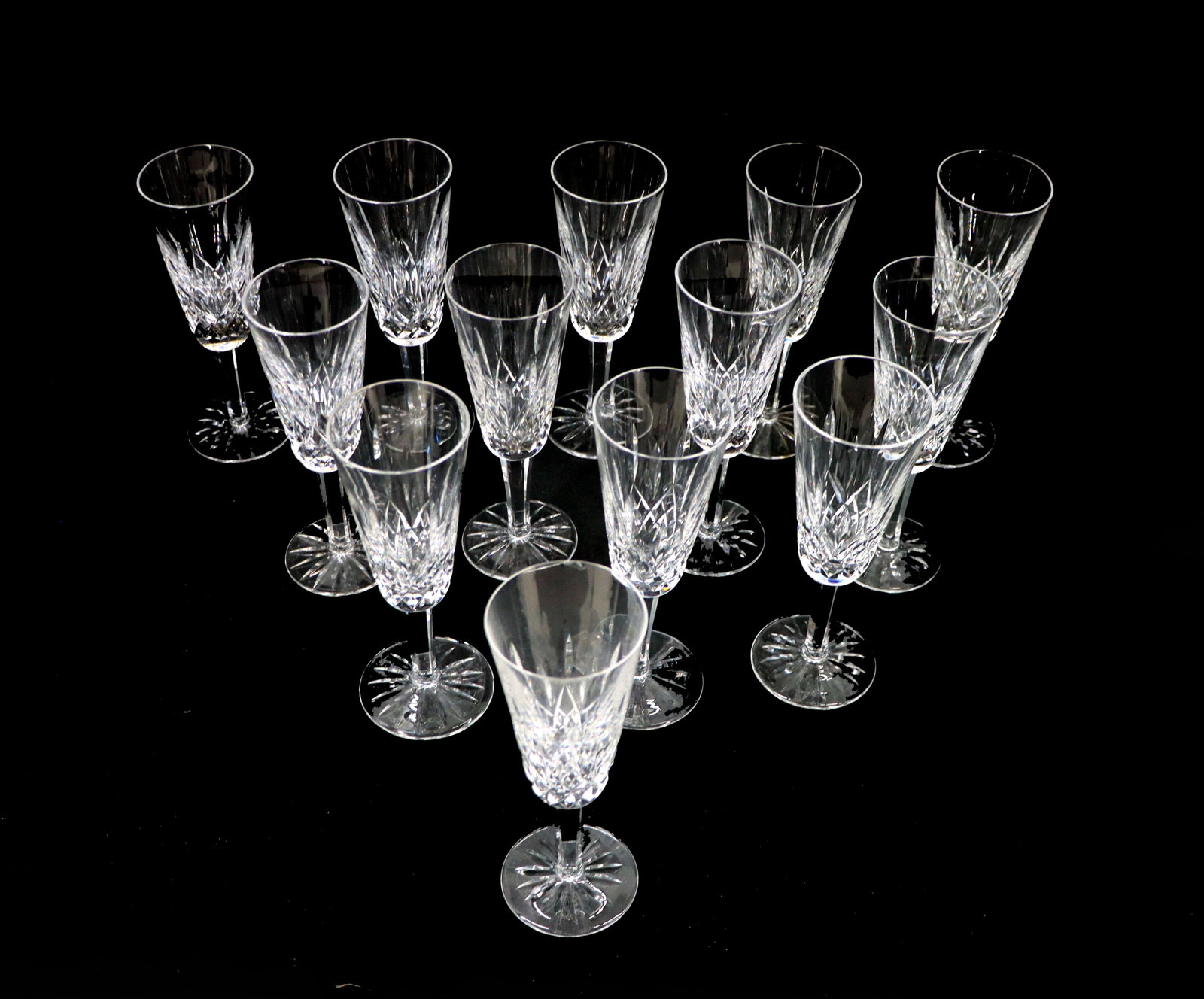 (12) Waterford Crystal Lismore Champagne Flutes: (12) Waterford Crystal Lismore Champagne Flutes. Marked on undersides. Size: 7 1/2 x 2 1/2 in. Waterford Crystal is a manufacturer of lead glass or “crystal,” especially in cut