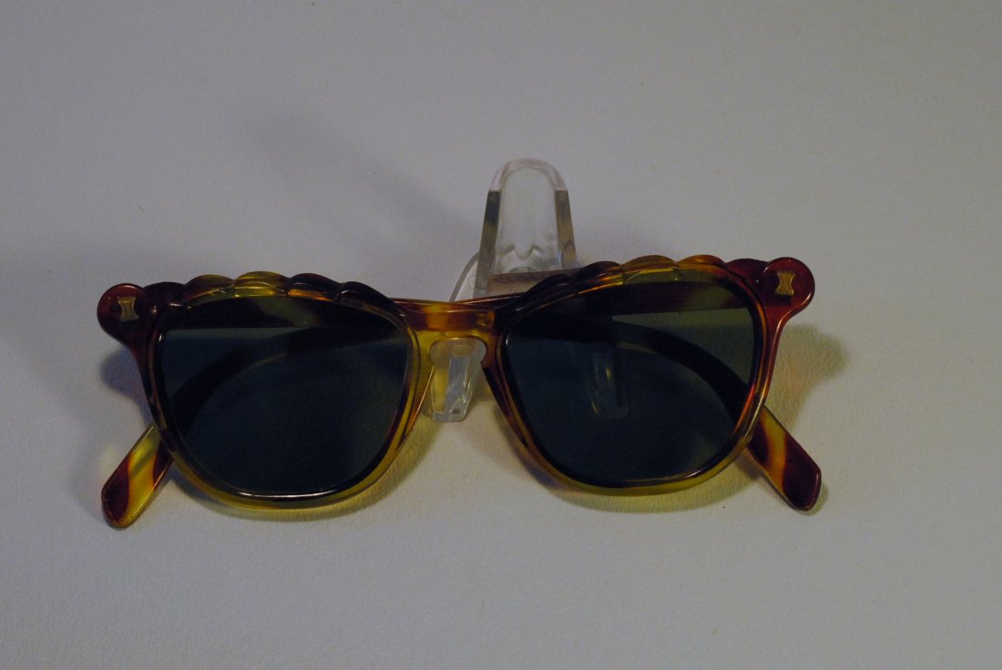 Mottled Brown and Green Sunglasses: Mottled green and brown translucent sunglasses with carving on tops of frames and depictions of gilt hourglasses.