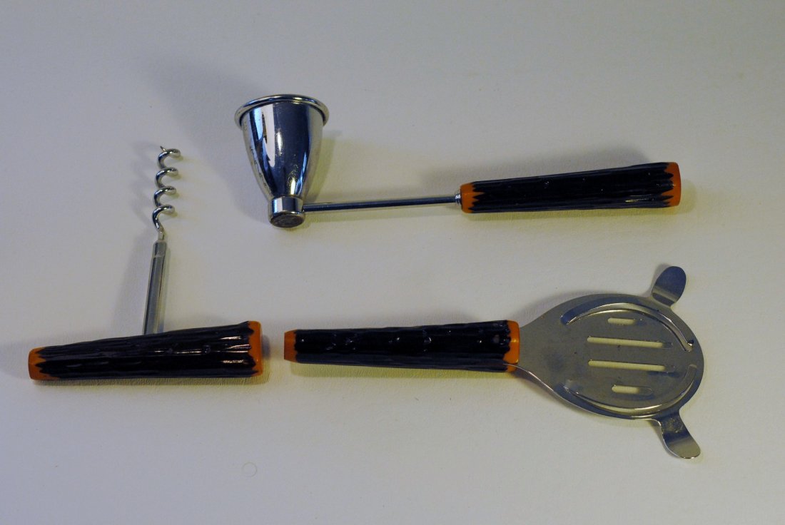 Bakelite Cocktail Utensils Set: Set of three Bakelite handled cocktail utensils including, corkscrew, a Bakelite handled jigger, and a Bakelite handled strainer. All handles are amber and dark brown Bakelite construction depicting t