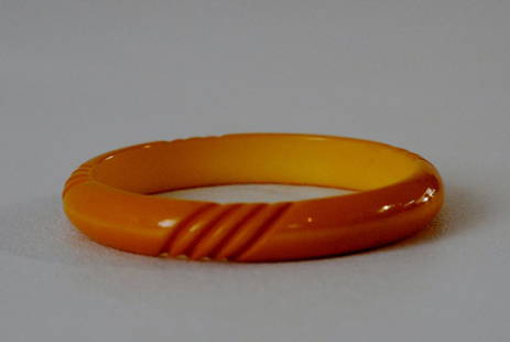 Thin Yellow Bakelite Bangle with Line Carvings: Yellow colored bakelite bangle, with thin design and four groups of line carvings