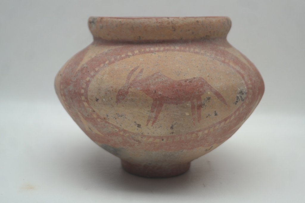 Antique Decorated Terracotta Earthenware Vessel: Antique earthenware vessel having footed base and red painted accents. With imagery of a stylized animal. Condition: Evidence of burning at base, with chip to base and rim. Height: 5 in