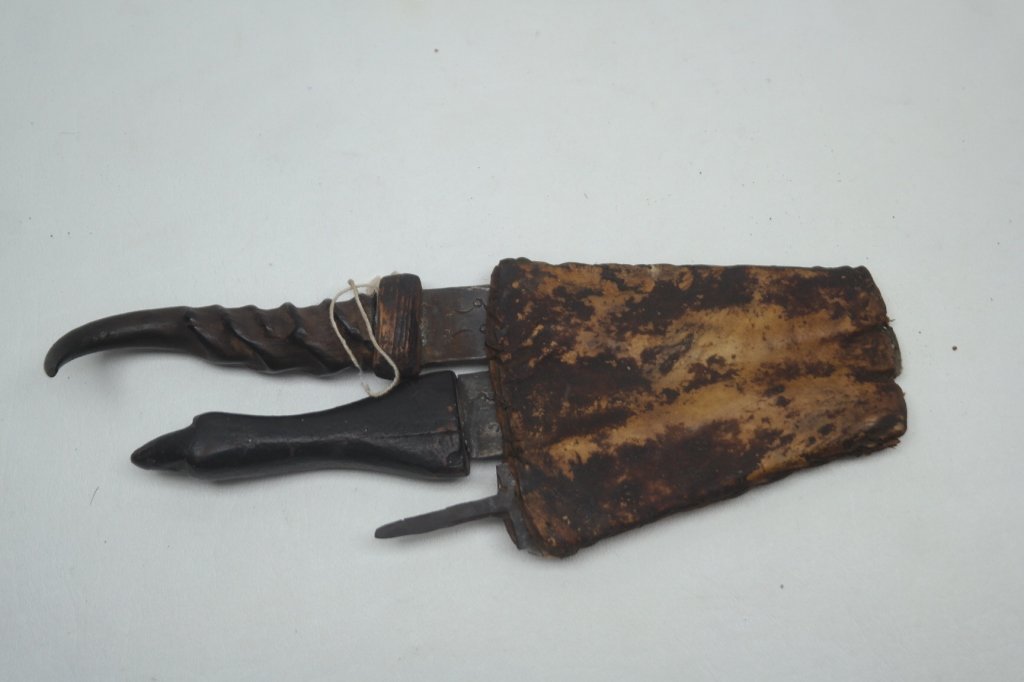 Antique African Daggers: Three antique African daggers in animal hide sheath and having highly carved handles. One having handle missing. Ex Museum Collection