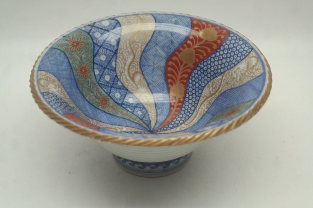 Antique Imari Porcelain Bowl: Antique porcelain bowl having geometric and floral motifs to interior. Rim having gilt stylized "rope" effect. Also with stylized waves to footed base. Base is marked and signed.