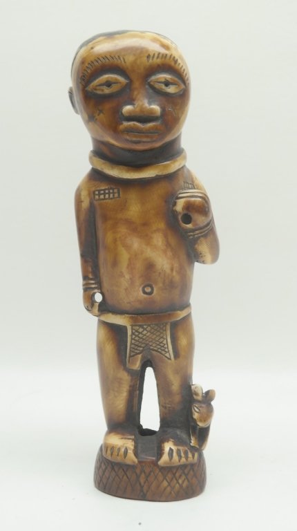 Antique Carved African Ivory Figure: Antique Carved African ivory figure in male form. Having almond shaped eyes. One hand is depicted holding an item over his shoulder. Having small animal at feet. Both are depicted on round and etched 