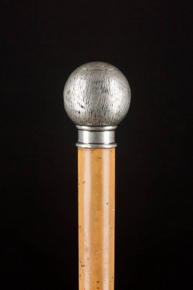 SPAZIERSTOCK MIT KUGELKNAUF Deutsch, nach 1888 Knauf: SPAZIERSTOCK MIT KUGELKNAUF Deutsch, nach 1888 Knauf aus Silber, Malakkarohrschuss, Metallzwinge. L. 90 cm. Silberknauf punziert mit Halbmond, Krone, Feingehalt '800' und Herstellerzeichen 'OS'. Auf d