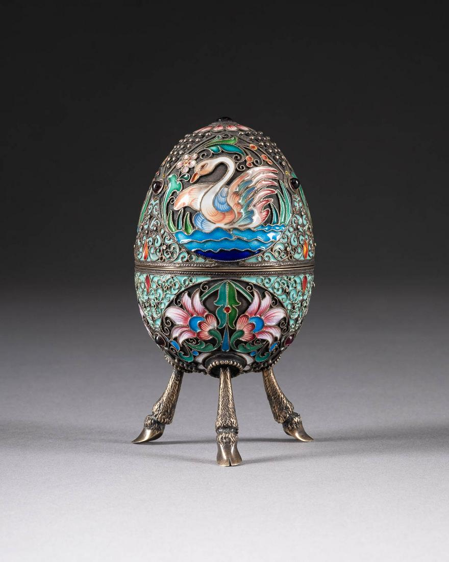 CLOISONNÉ-EMAIL-EIDOSE: A SILVER-GILT AND CLOISONNÉ ENAMEL EGG-SHAPED BOX 2nd half 20th century The egg-shaped box with lift-off top decorated with swans, flowers and stylised scrolls in vari-coloured cloisonné enamel on s