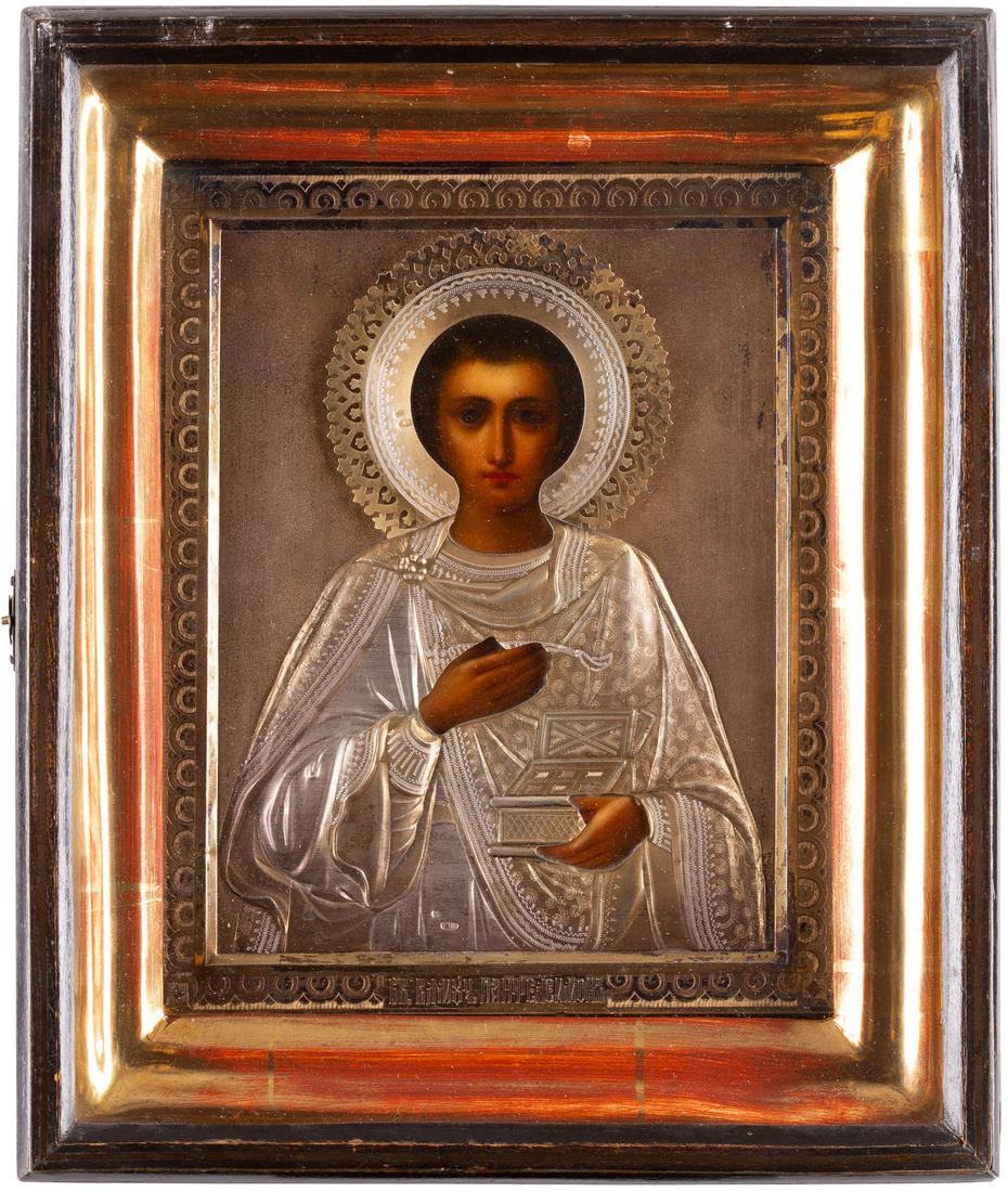 AN ICON SHOWING ST. PANTELEIMON WITH A SILVER-GILT: AN ICON SHOWING ST. PANTELEIMON WITH A SILVER-GILT OKLAD WITHIN A KYOT Russian, early 20th century (icon), Russian, Moscow, 1908-1917 (oklad) Oil on wood panel with velvet backing. Overlaid with an en