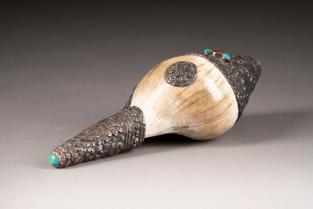 A METAL WRAPED SANKHA China (Tibet), 19th/20th c. Conch/metal. Decorated with animal patterns and ge (1 of 2)