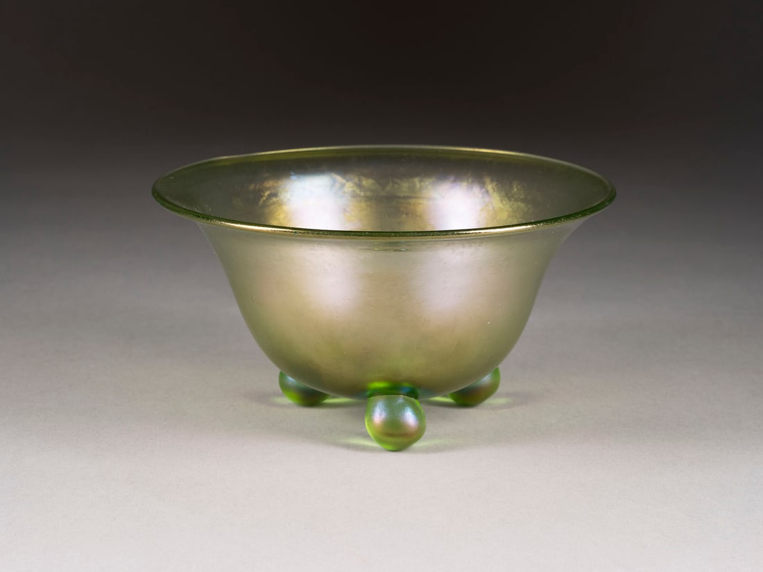 GEFUSSTE SCHALE 'OLYMPIA': GEFUSSTE SCHALE 'OLYMPIA' Boehmen, Klostermuehle, Loetz Witwe, um 1896 Hellgruenes Glas, irisierend. D. 17 cm, H. 9 cm. Auf drei Kugelfuessen glockenfoermige Schale. Sehr min. Gebrauchsspuren.