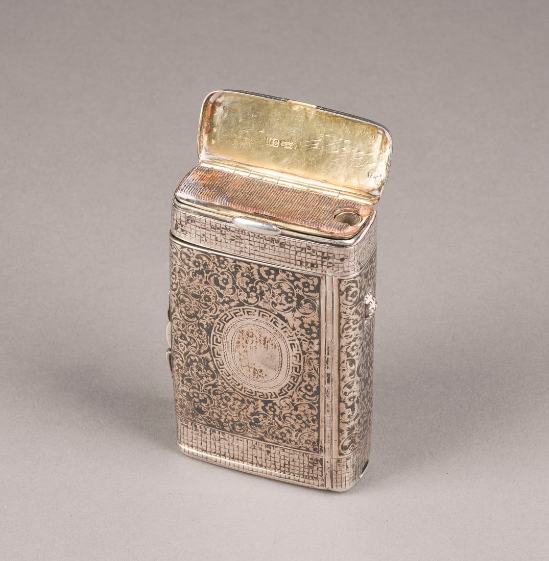 SELTENES NIELLO-ZIGARETTEN-ETUI MIT FOTORAHMEN, LUNTEN- UND STREICHHOLZFACH: A RARE SILVER AND NIELLO CIGARETTE CASE WITH PHOTO FRAMES Russian, Moscow, Ivan Saltikov, 1886 Of rectangular form. The hinged cover and bottom decorated with scrolling foliage. Gilt interior. With ve