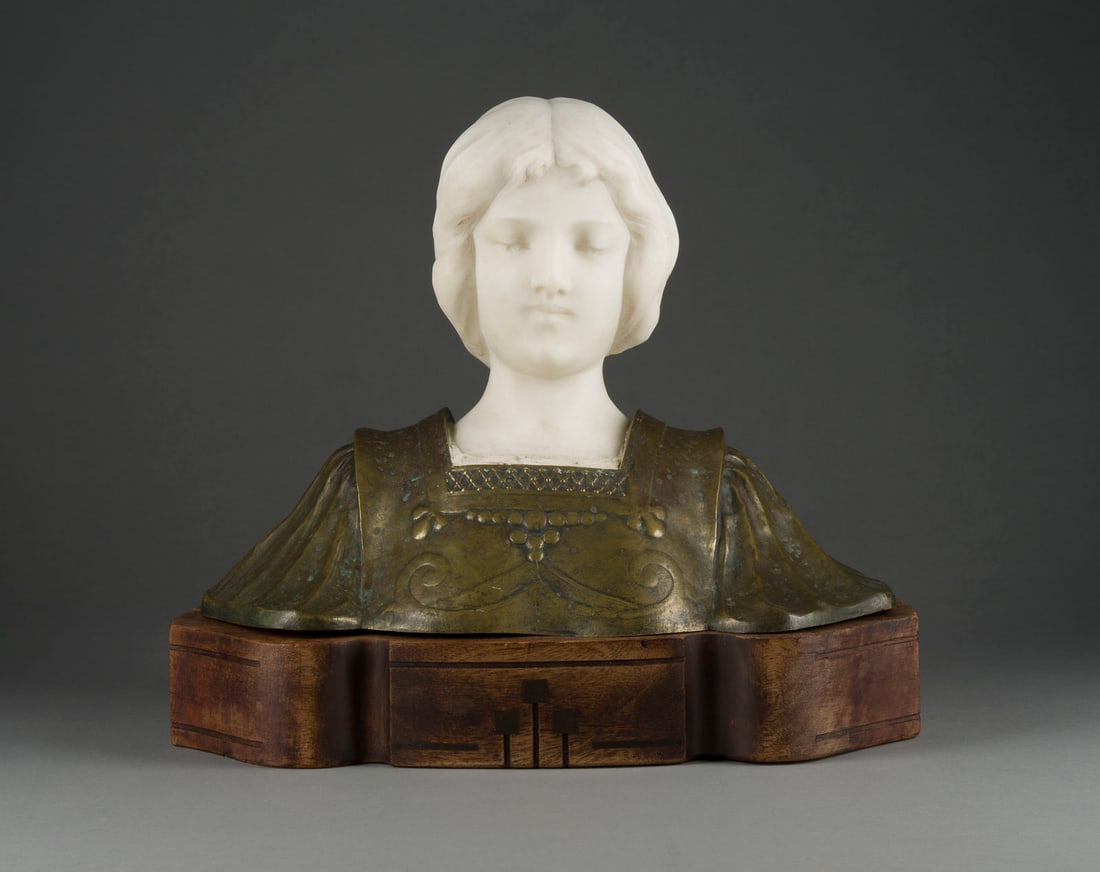 UNBEKANNTER BILDPLASTIKER 'COQUIO' FRAUENBUeSTE: UNKNOWN SCULPTOR 'COQUIO' Active at the beginning of the 20th century WOMAN'S BUST Alabaster, bronze, light patina, on a wooden base. H. 36, w. 42, d. 24 cm. Inscribed 'Coquio' on the back of the shou