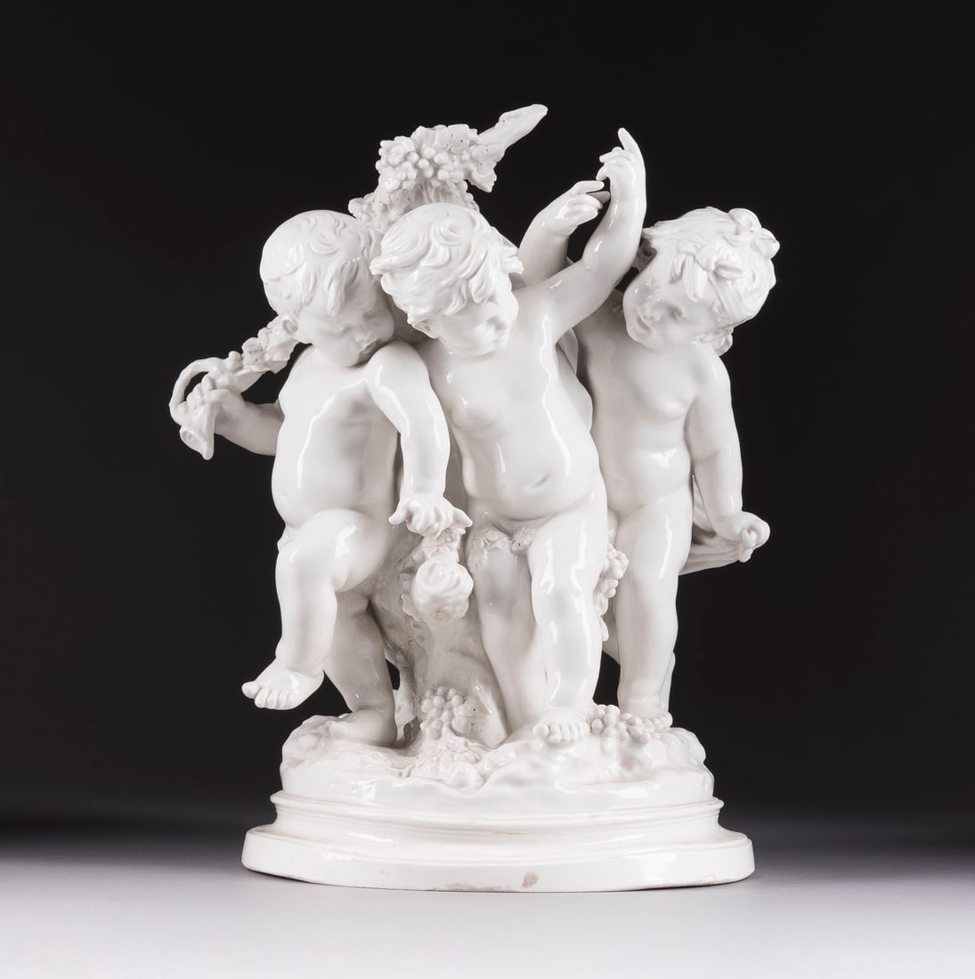 AUGUSTE MOREAU | PUTTEN MIT WEINTRAUBEN: AUGUSTE MOREAU 1861 Dijon - 1906 Paris (nach) PUTTEN MIT WEINTRAUBEN Italien, Neapel, Capodimonte, 20. Jh. Weißporzellan, glasiert. H. 42 cm. Unterglasurblaue 'N'-Marke unter Krone, bez. ' a. moreau'