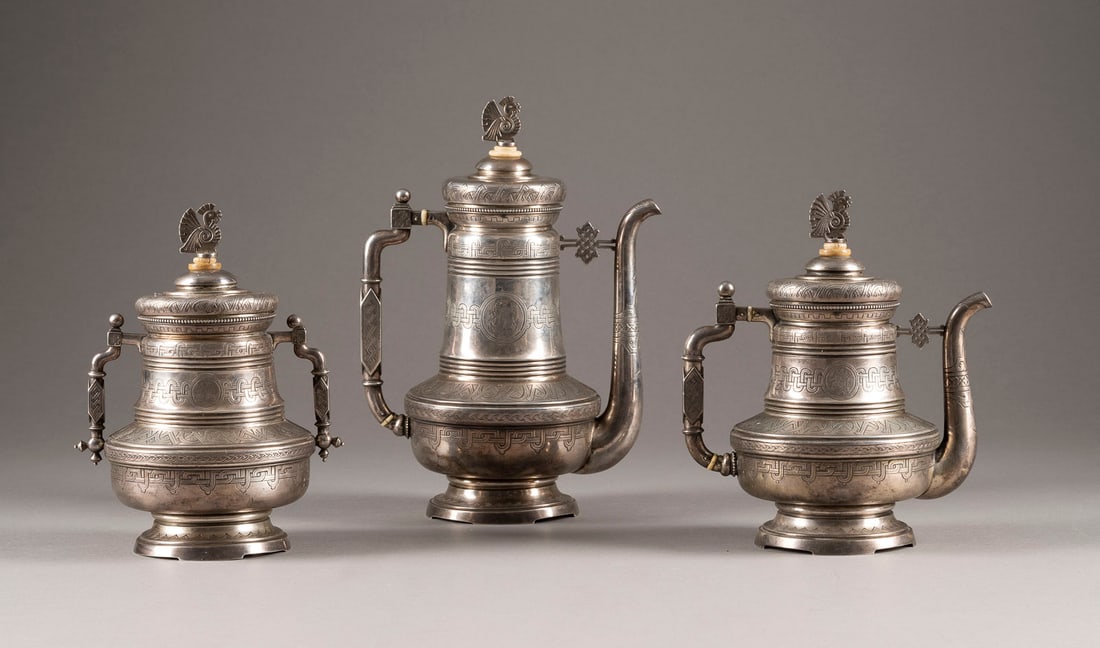 A VERY FINE THREE-PIECE SERVICE IN THE PAN-SLAVIC STYLE: A VERY FINE THREE-PIECE SERVICE IN THE PAN-SLAVIC STYLE Russian, Moscow, Ivan Khlebnikov, 1879 Comprising a sugar pot, a teapot, and a coffee pot. The bodies finely engraved with ornament inspired by