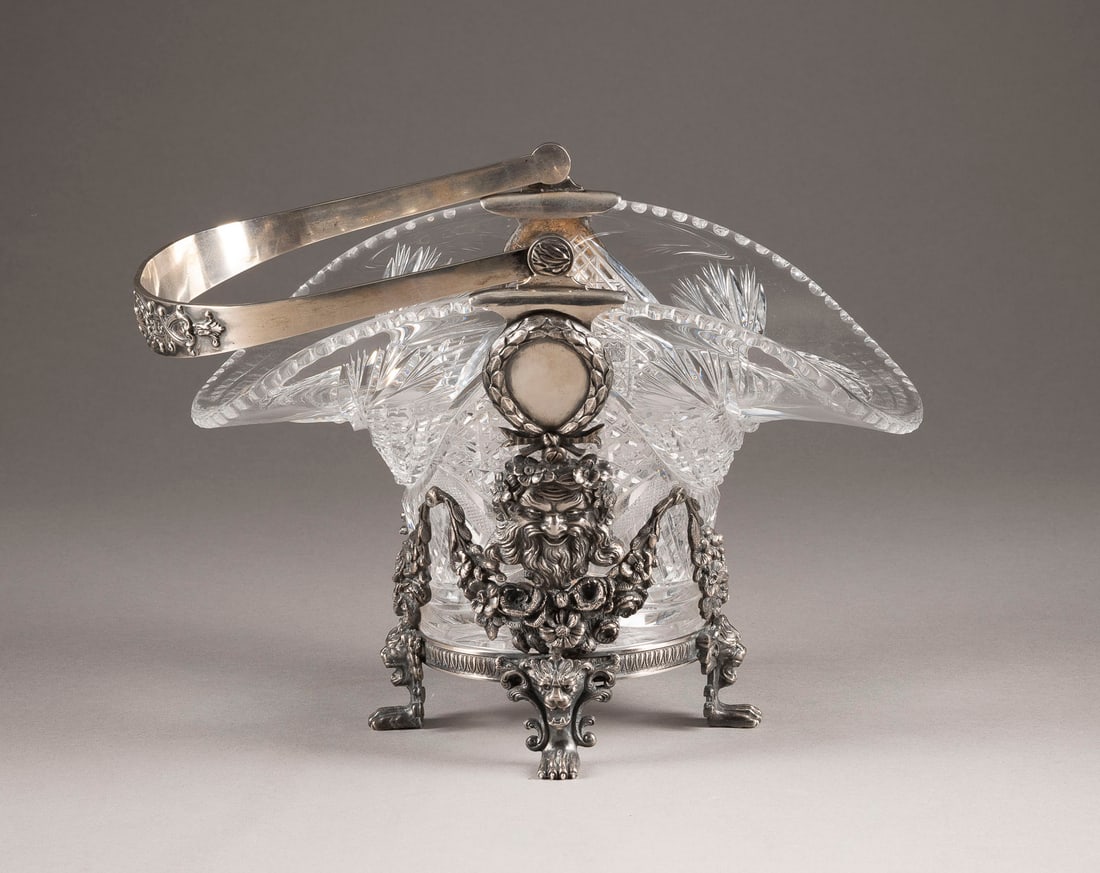 A SILVER-MOUNTED CUT-GLASS BASKET WITH HANDLE: A SILVER-MOUNTED CUT-GLASS BASKET WITH HANDLE Russian, St. Petersburg, 1908-1917 The silver mount with chased ribbon-tied swags, lion heads and satyr masks. The silver handles with chased foliate moti