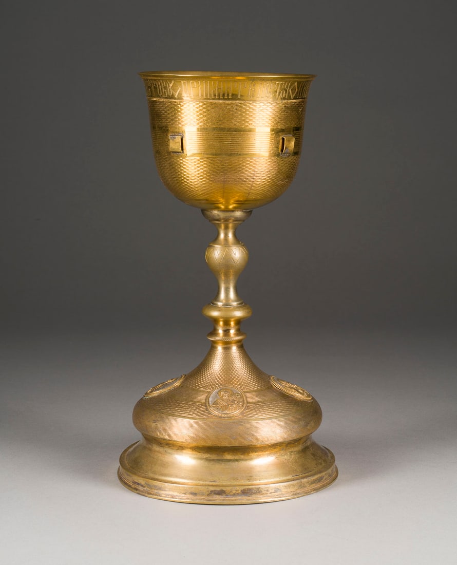 A BRASS CHALICE SHOWING THE FOUR EVANGELISTS AND THE CRUCIFIXION: A BRASS CHALICE SHOWING THE FOUR EVANGELISTS AND THE CRUCIFIXION Russian, late 19th century The body with engine-turning. 28.4 cm high. ABENDMAHLSKELCH MIT DEN VIER EVANGELISTEN Russland, Ende 19. Jh.