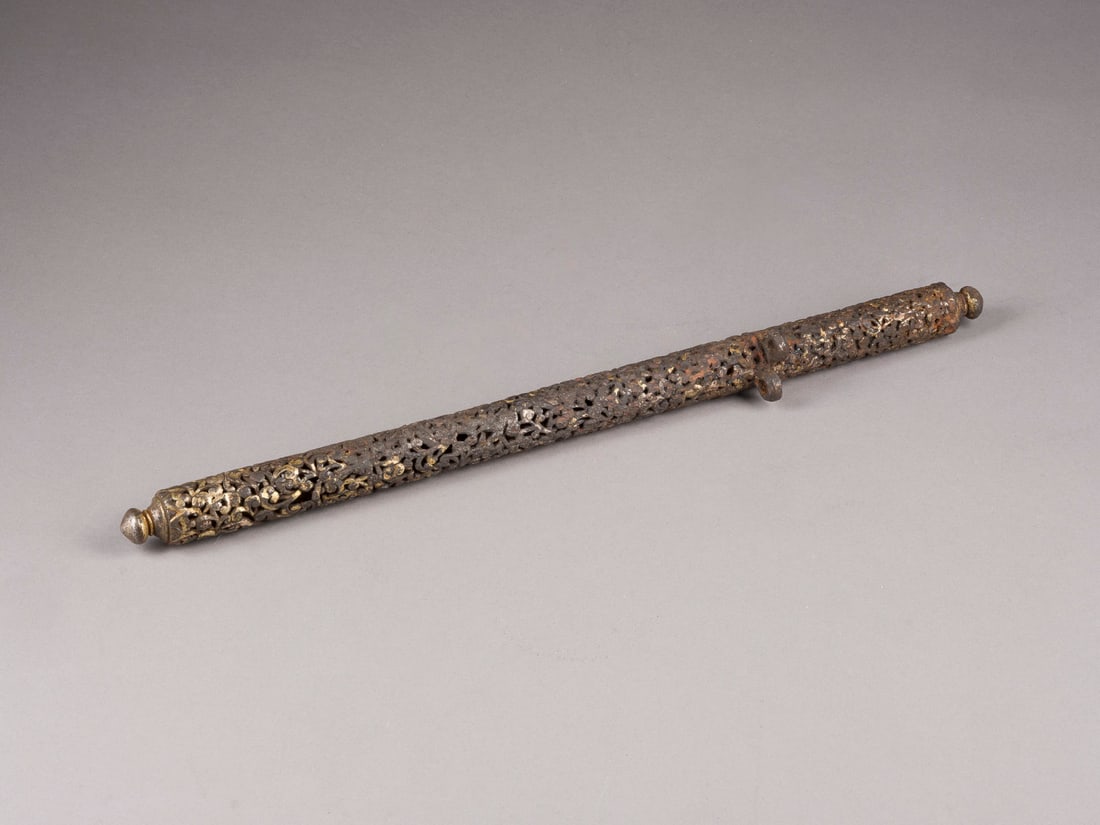 EIN DURCHBROCHENER SCHREIBZEUGBEHAELTER AUS EISEN: A RETICULATED IRON PEN CASE Tibet, 18th century or earlier Metal. L. 38.5 cm. The pen case is decorated with openwork scrolling patterns, the ends in the form of lotus buds. With traces of age and gil
