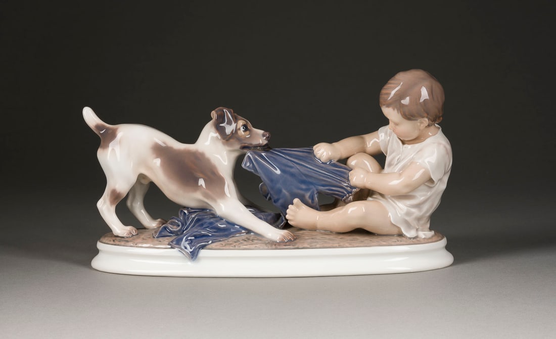 | JUNGE MIT HUND: JUNGE MIT HUND Dänemark, Dahl Jensen, ab 1930 Porzellan, polychrom gefasst. H. 18 cm, L. 33,5 cm. Grüner Stempel 'DJ' unter Krone, 'Copenhagen/Denmark', Modellnr. 1072, Malersignatur 'E.K', bez.