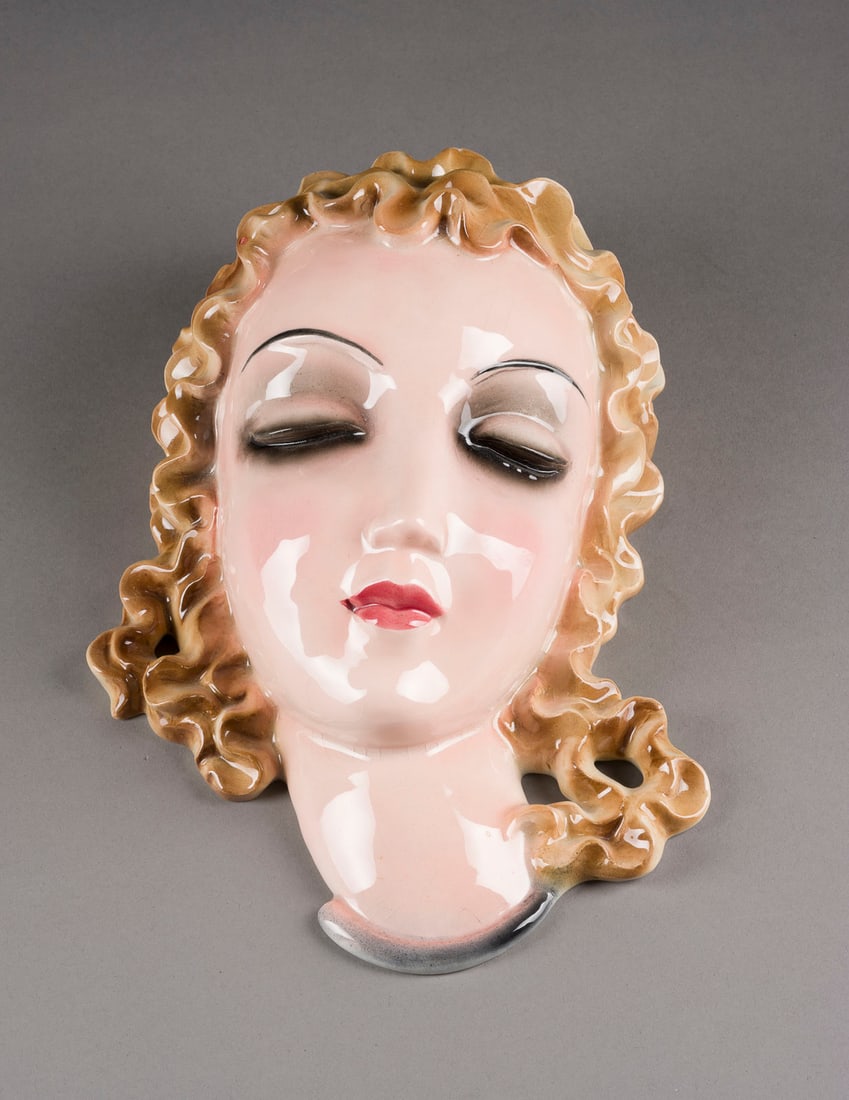 | WANDMASKE 'FRAUENKOPF': WANDMASKE 'FRAUENKOPF' Österreich, Wien, Goldscheider'sche Porzellanmanufaktur und Majolikafabrik, 1. Hälfte 20. Jh. Keramik, heller Scherben, farbig staffiert. L. 25 cm. Herstelleretikett,