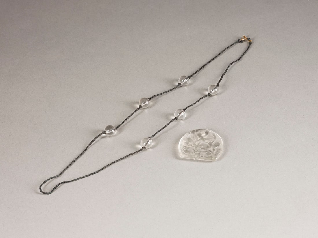 LALIQUE | COLLIER MIT MISTELZWEIGDEKOR: LALIQUE COLLIER MIT MISTELZWEIGDEKOR Frankreich, Lalique, 1920 Pâte de verre, Bergkristallkugeln, Seidenkordel, Kettenverschluss 14K Gold. L. 4,5 cm (Anhänger), L. 37 cm (Kordel). Unten rechts bez.