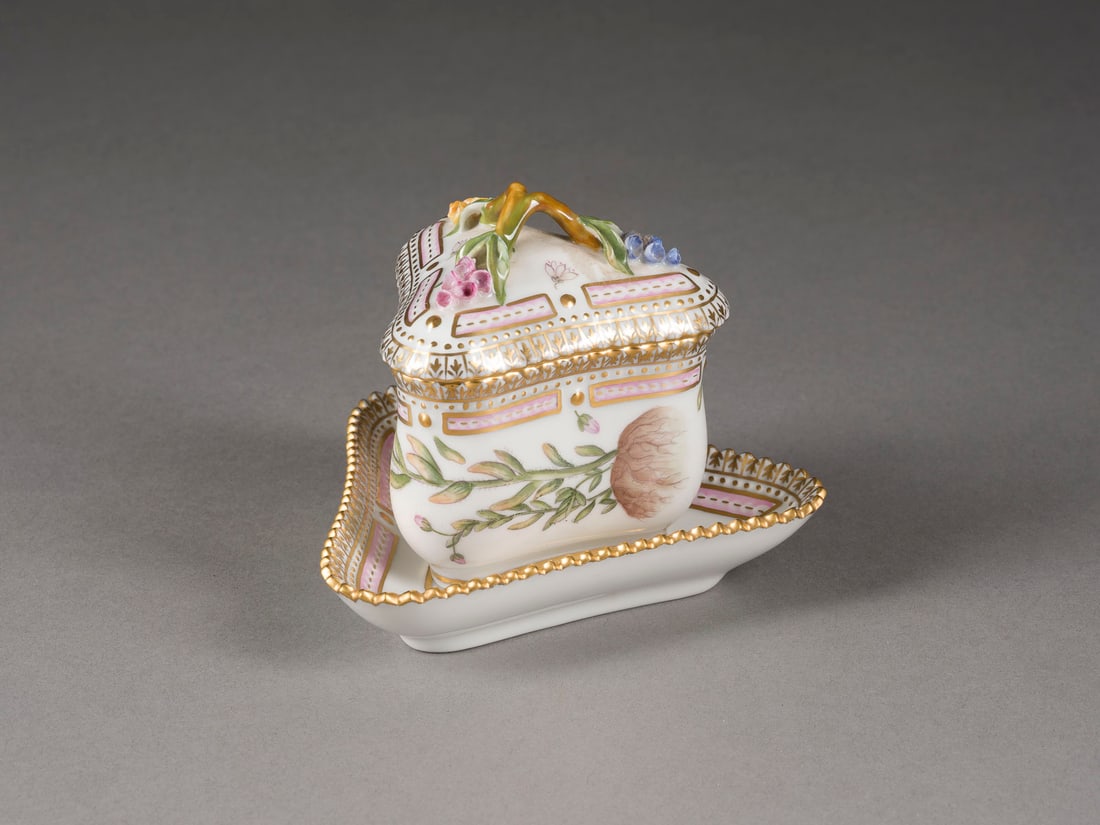 | PUDDINGBECHER MIT UNTERTASSE 'FLORA DANICA': PUDDINGBECHER MIT UNTERTASSE 'FLORA DANICA' Dänemark, Royal Copenhagen, 1980-1984 Porzellan, polychrome Malerei und Goldstaffage. H. 7 cm (ohne Griff), L. 9,5 cm (Untertasse). Grüne Manufakturmarke,