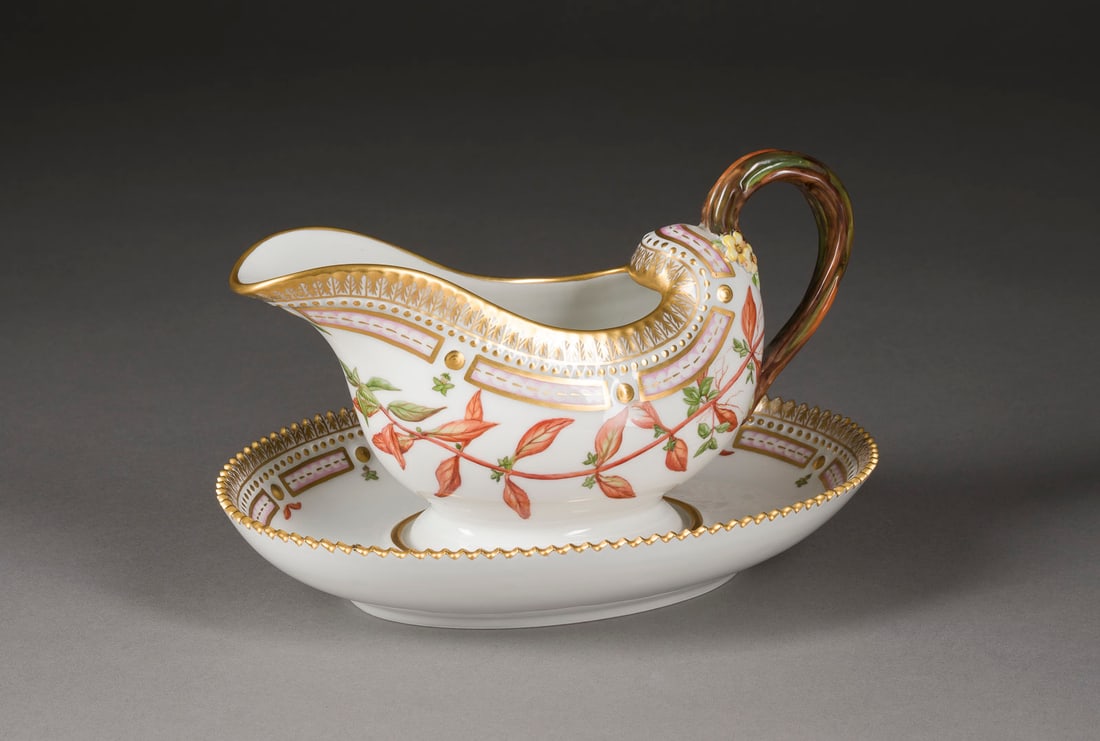 | SAUCIERE AUF UNTERSETZER 'FLORA DANICA': SAUCIERE AUF UNTERSETZER 'FLORA DANICA' Dänemark, Royal Copenhagen, 1966 Porzellan, polychrome Malerei, Goldstaffage. L. 23,5 cm, H. 14 cm. Unterglasurblaue Wellenmarke, grüner Manufakturstempel, Ma