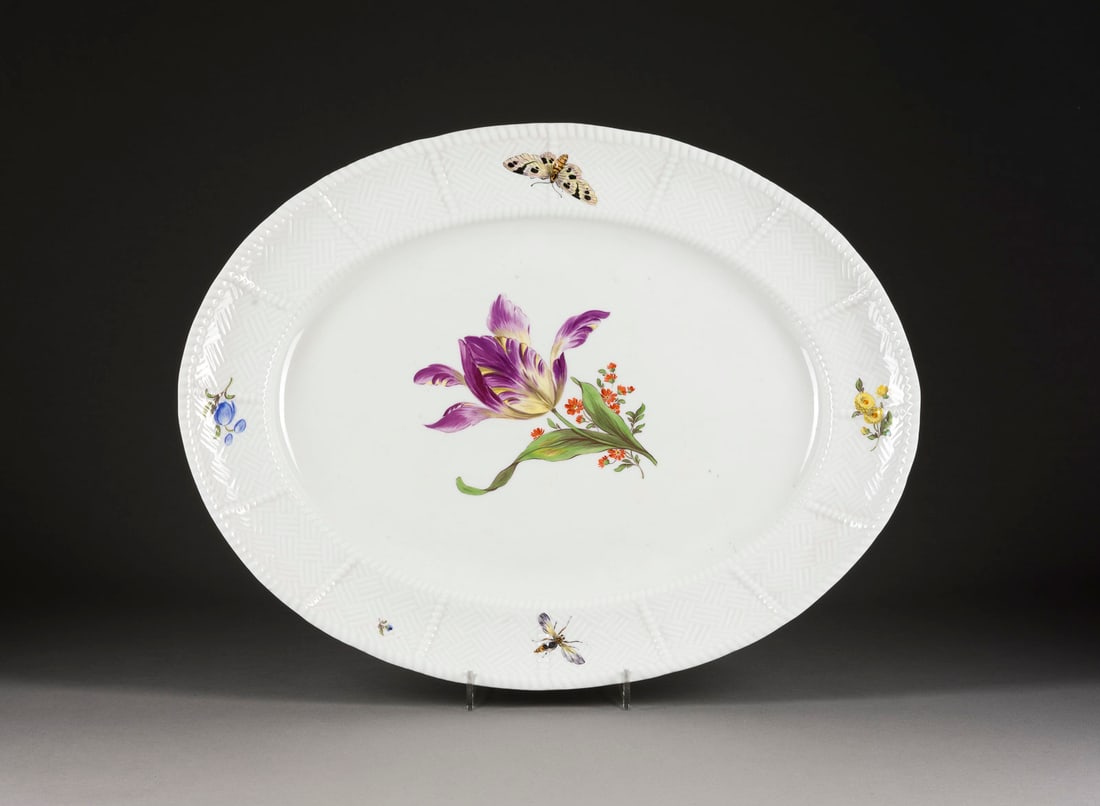 | SERVIERPLATTE MIT BLUMENMALEREI UND INSEKTEN: SERVIERPLATTE MIT BLUMENMALEREI UND INSEKTEN Deutsch, Meissen, Porzellan, polychrome Malerei. L. 47 cm. Unterglasurblaue Schwertermarke, Press- und Modellnr. Relief: Sulkowski.SERVIERPLATTE MIT