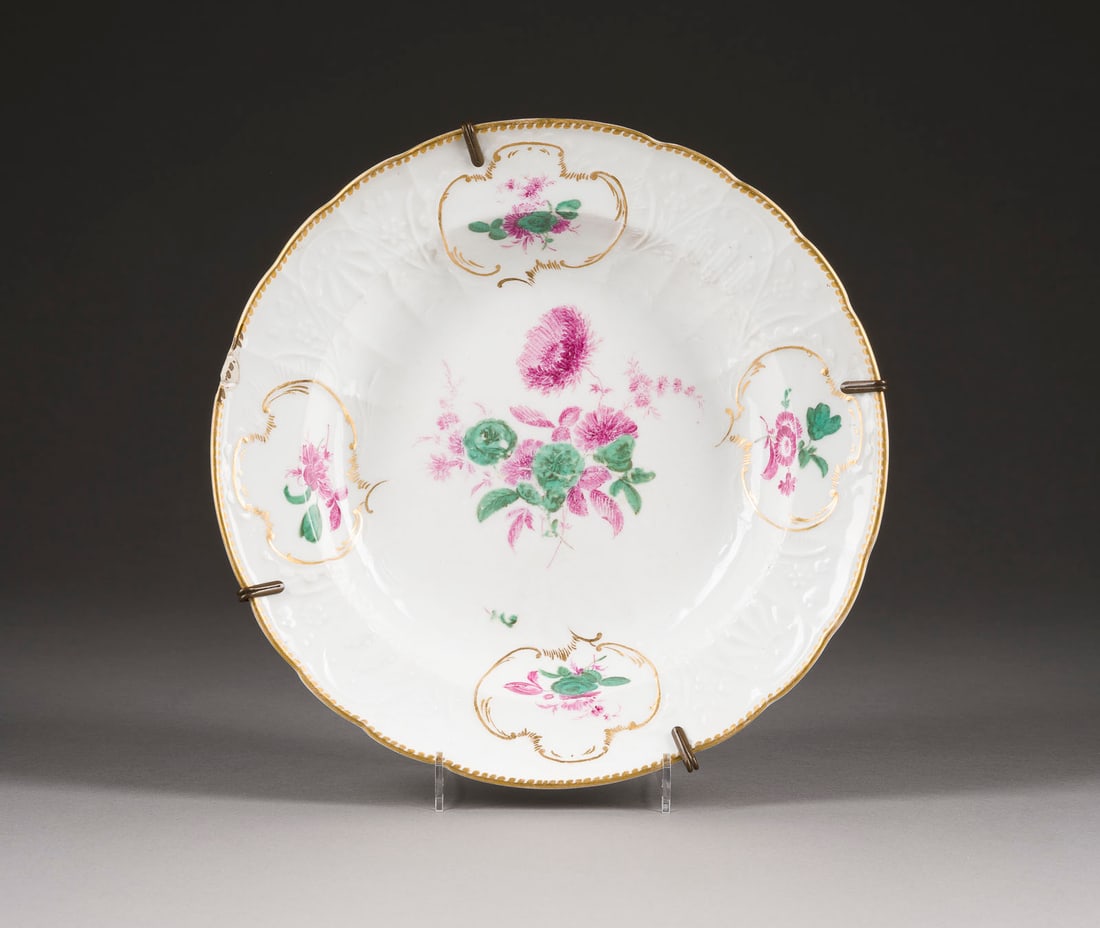 | TELLER MIT 'BLUMENMALEREI': TELLER MIT 'BLUMENMALEREI' Deutsch, Meissen, 1765-1774 Porzellan, Camaieumalerei in Grün und Purpur, Goldstaffage. D. 23,5 cm. Unterglasurblaue Punktschwertermarke, Pressnummer. Form: Dulong. 1.