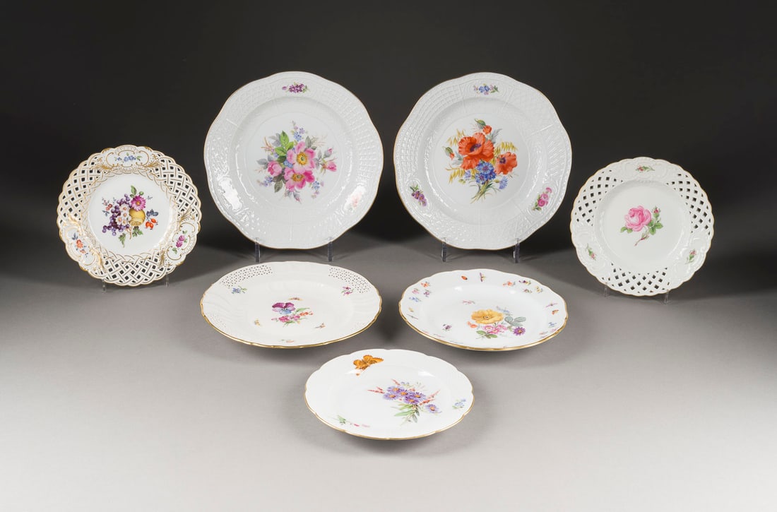 | SIEBEN TELLER: SIEBEN TELLER Deutsch, Meissen, KPM Berlin, Anfang 20. Jh. Porzellan, polychrome Malerei, dezente Goldstaffage. D. 18,5-24,5 cm. Unterglasurblaue Schwertermarke (eine davon Knaufschwerter), Press-