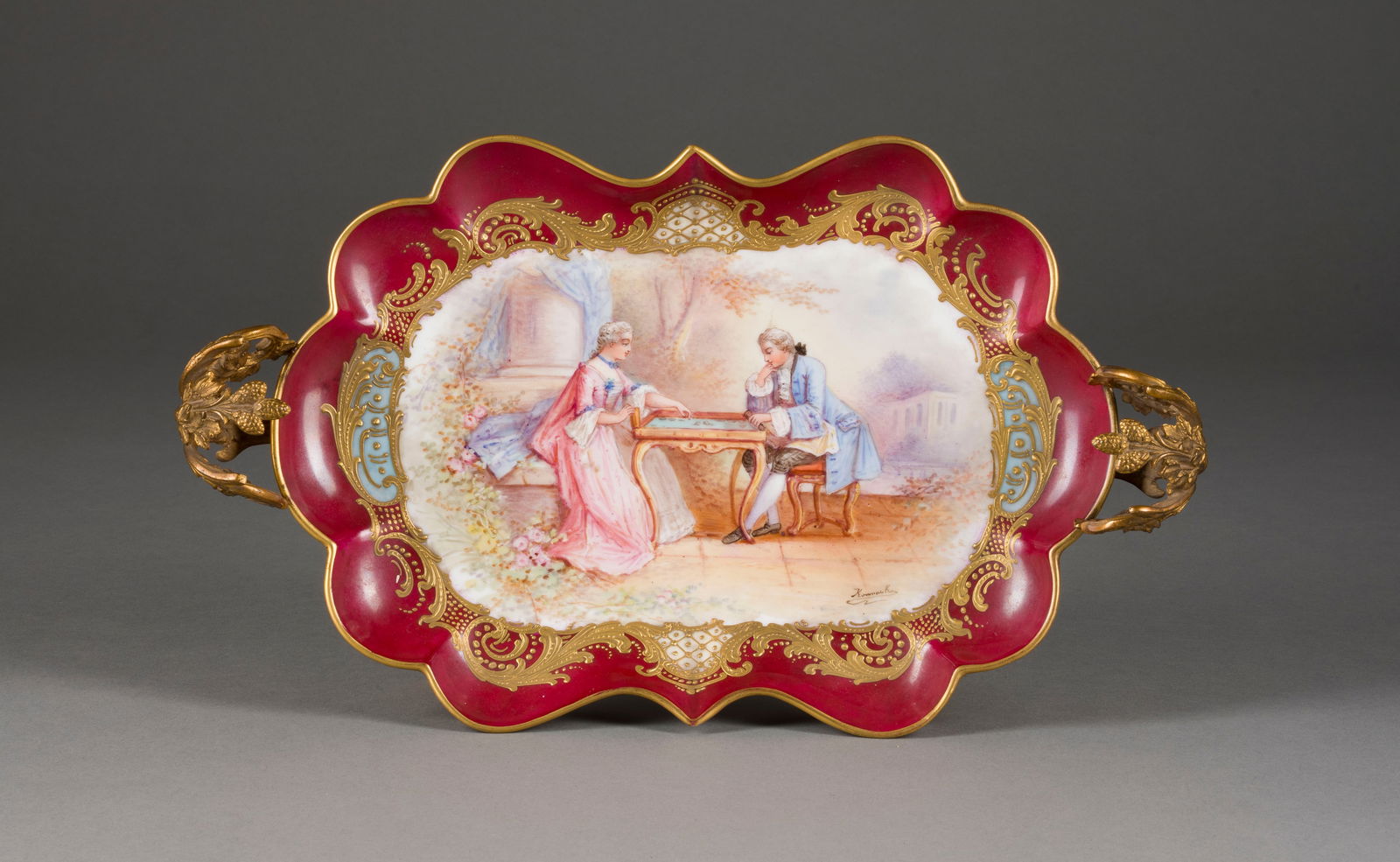 | NAPOLEON III.-HENKELSCHALE: NAPOLEON III.-HENKELSCHALE Frankreich, Sèvres, 19. Jh. Porzellan, polychrome Malerei, teilweise Purpurfond, Goldstaffage, Metallmontierung. L. 34,5 cm. Firmenmarken, Markenzeichen von 'Château des