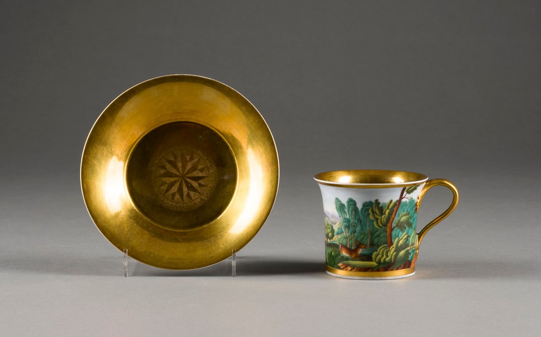 | TASSE UND UNTERTASSE MIT JAGDSZENE: TASSE UND UNTERTASSE MIT JAGDSZENE Böhmen, Horní Slavkov, Georg Lippert, 19. Jh. Porzellan, polychrome Malerei, Goldstaffage. H. 7,2 cm (Tasse), D. 15 cm (Untertasse). Unterglasurblaue