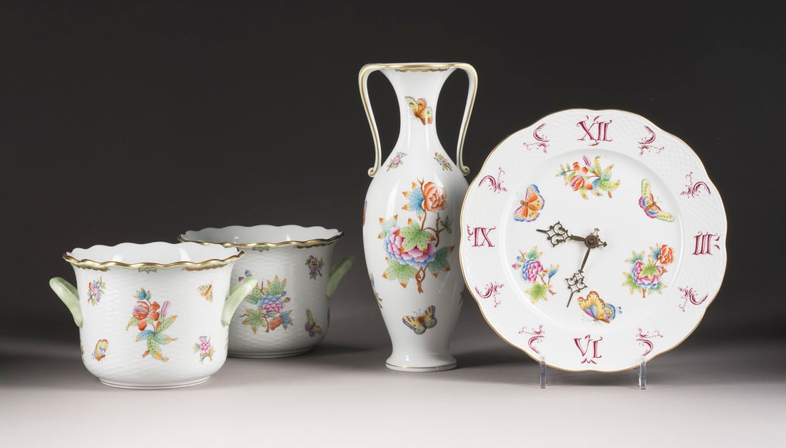 | WANDUHR, VASE UND ZWEI CACHEPOTS 'VICTORIA': WANDUHR, VASE UND ZWEI CACHEPOTS 'VICTORIA' Ungarn, Herend, 20. Jh. Porzellan, polychrome Malerei, Goldstaffage. H. 13,5 (Cachepot) und 33,5 cm (Vase), D. 28 cm (Uhr). Aufglasurblauer