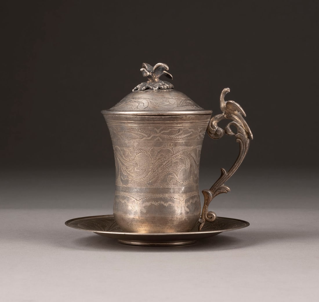 | DECKELTASSE AUF UNTERTASSE: DECKELTASSE AUF UNTERTASSE Wohl Marokko, 19. Jh. Silber. H. 13 D. 13,5 (Untertasse), 381 g. Unleserlich punziert.DECKELTASSE AUF UNTERTASSE