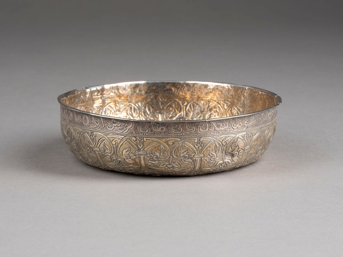 | PERSISCHE SCHALE MIT FLORALDEKOR: PERSISCHE SCHALE MIT FLORALDEKOR Persien, 16. / 17. Jh. Silber, getrieben, part. vergoldet. D. 13,7 cm, 175 g. Flächendeckend verziert mit Floraldekor, Lippenrand mit umlaufender Inschrift.