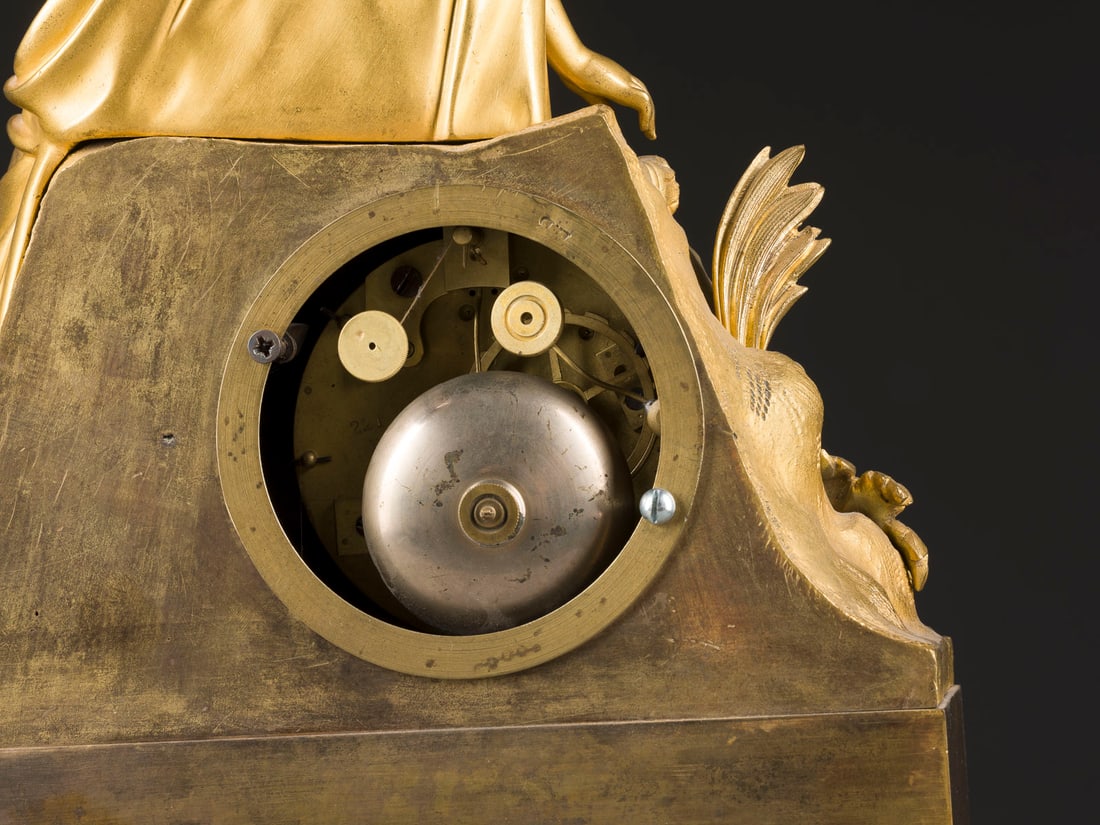 | CHARLES X.-TISCHUHR MIT ALLEGORIE: CHARLES X.-TISCHUHR MIT ALLEGORIE um 1830 Bronze, Metall, vergoldet, Stahl. 46 x 33 x 12 cm. Hoher Rechtecksockel mit Zierfries und Ornamentik über ornamentierten Füßen und Zarge. Auf einem Felsen