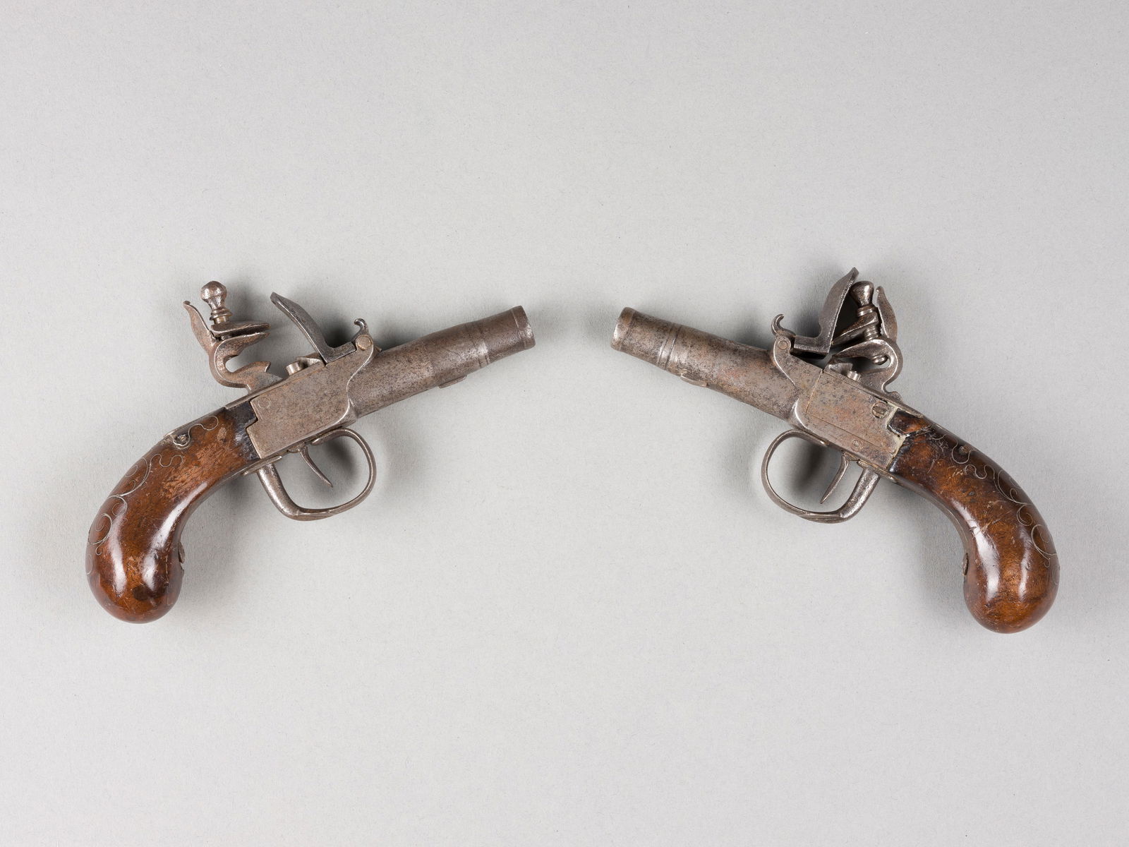 | PAAR REISEPISTOLEN: PAAR REISEPISTOLEN Ende 18. Jh./um 1800 Holz, Eisen. L. 15,5 cm. Auf der Unterseite des Laufs unterschiedliche Beschusszeichen: 'V', 'R', 'G', jeweils im Oval. Polierter Holzgriff mit feinen,