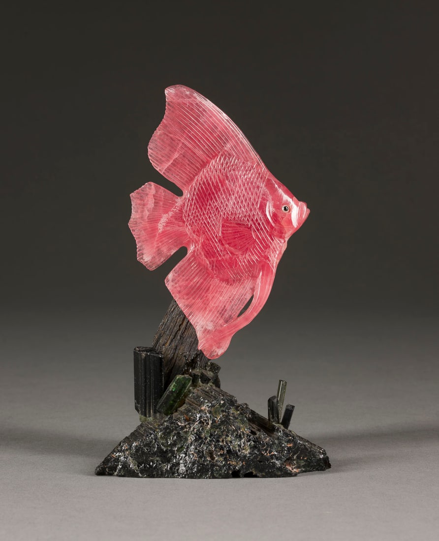 | SCHMUCKSTEIN-SKALAR: SCHMUCKSTEIN-SKALAR Deutsch, wohl Idar-Oberstein, 20. Jh. Leicht transparenter Rhodochrosit, grüner Turmalin (Verdelit). 15 x 9 x 6,5 cm. Auf grünlichem Sockel vollplastische, naturalistische Schnit