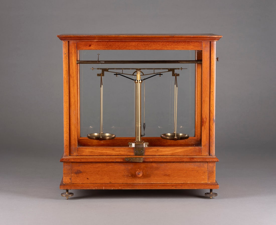 | APOTHEKER-REZEPTUR-STANDWAAGE: APOTHEKER-REZEPTUR-STANDWAAGE Deutsch, um 1920 Holz, Glas, Metall, Stahl. 43,5 x 42,5 x 23,5 cm. Bez. 'Paulus & Thewalt Höhr'. Auf verstellbaren Metallfüßen (die hinteren unvollständig),