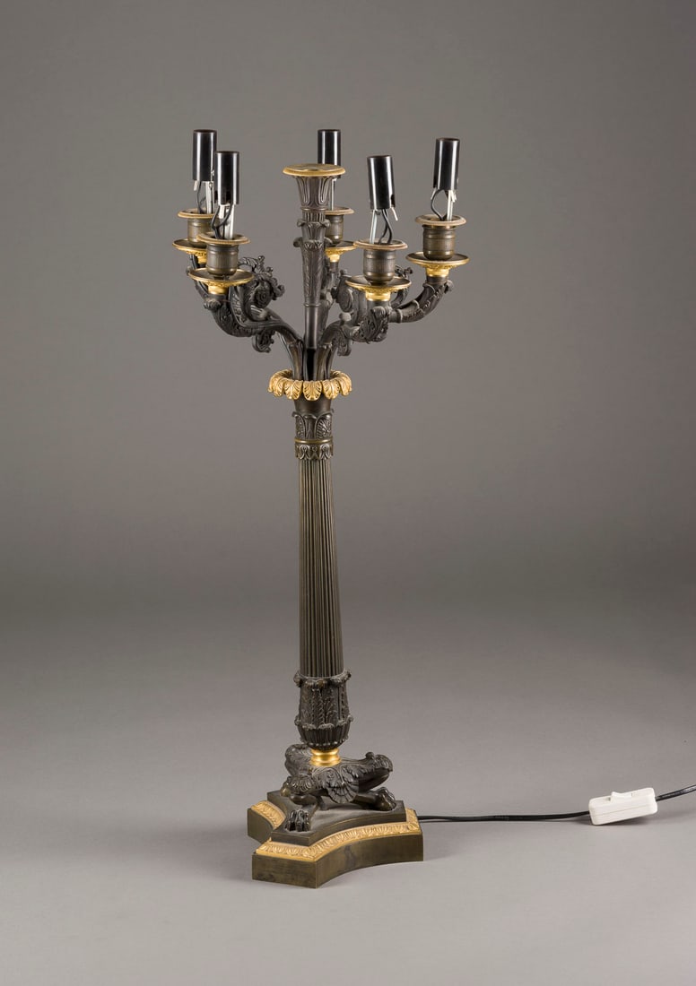 | EMPIRE-KANDELABER: EMPIRE-KANDELABER um 1810 Bronze, part. dunkel patiniert, part. vergoldet. H 67 cm, D. ca. 28 cm. Über Dreipassplinthe blattverzierte Tatzenfüße und kannelierter Schaft. Sechsflammig. Fünf